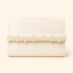 An ivory clutch bag with a horizontal band of pearls and crystals across the front, set against a solid cream background.