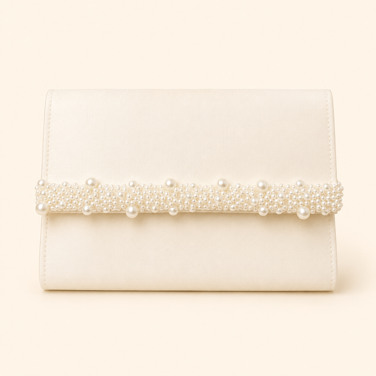 An ivory clutch bag with a horizontal band of pearls and crystals across the front, set against a solid cream background.