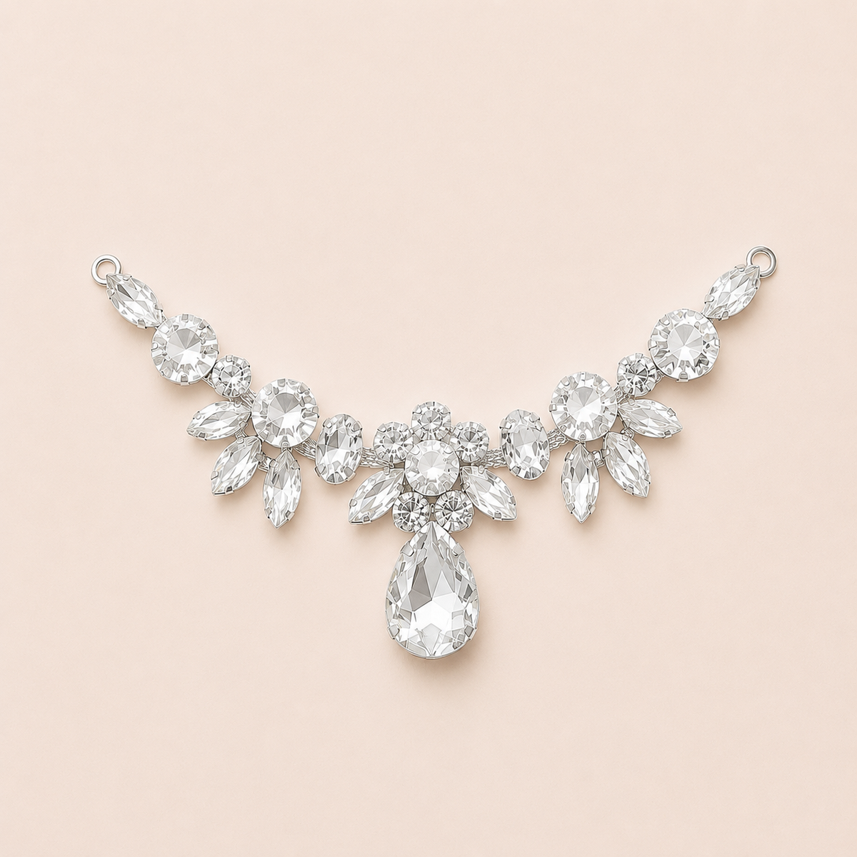 A silver-toned bridal crown necklace featuring clear teardrop, marquise, oval, and round crystals, arranged in a floral crown design on a soft peach-pink background.